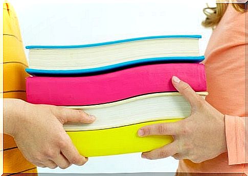 children holding a stack of books together