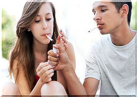 smoking among teenagers: boy with cigarette lights a girl's cigarette