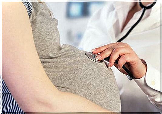 doctor listens to pregnant belly with stethoscope