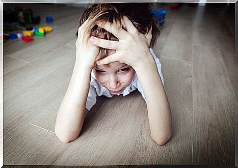 Stressed child lies on the floor and holds his head.