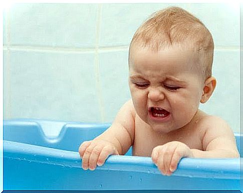 baby in bath tub, looks frustrated