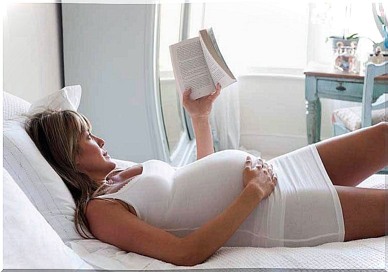 pregnant woman reading in bed