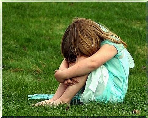 Girl sitting crouched on grass