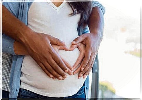 supplements for pregnant women: man and pregnant woman hold the pregnant belly with hands forming a heart