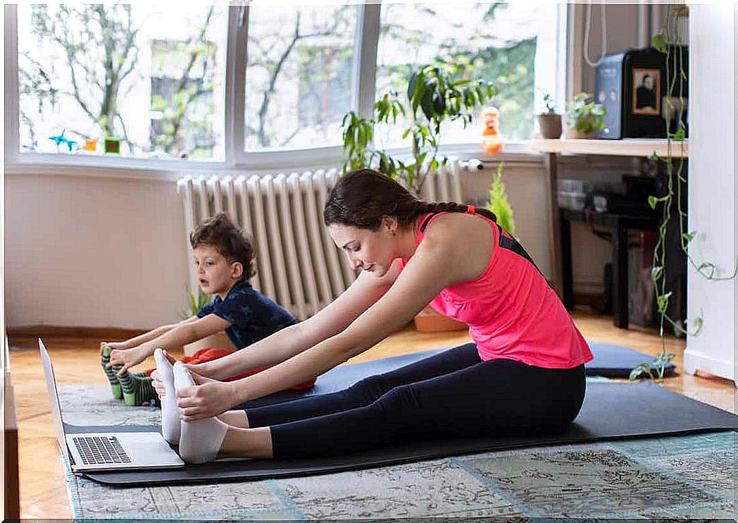 A mother and her young children stretch when they follow a training routine on the computer.