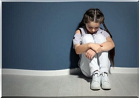 Girl sitting by wall.