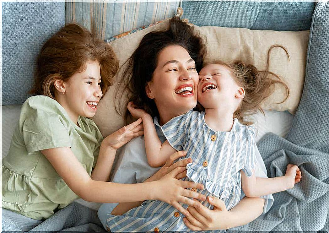 A mother cuddling in bed with her two young daughters.