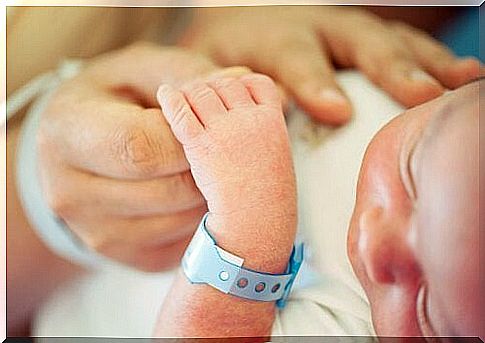 Newborn baby holds in mother's hand.