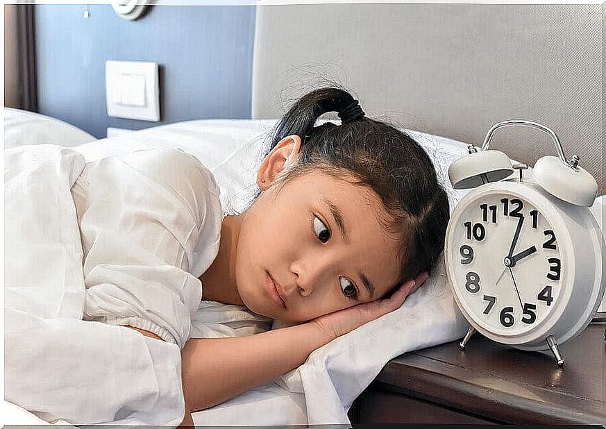 awake child in bed next to alarm clock