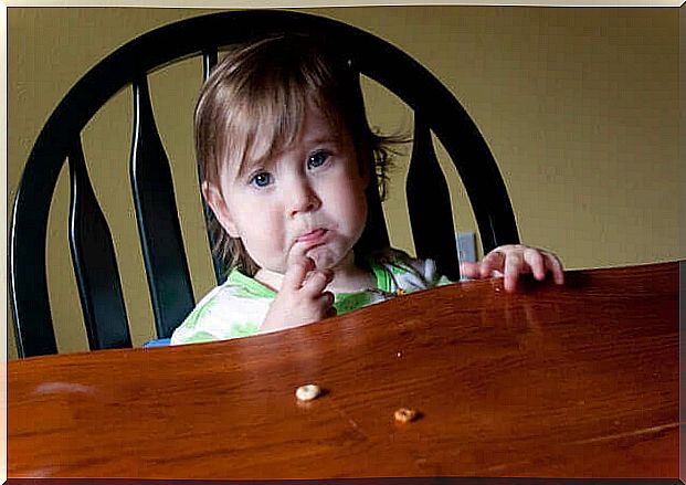 A child is sitting at the dinner table looking stressed.