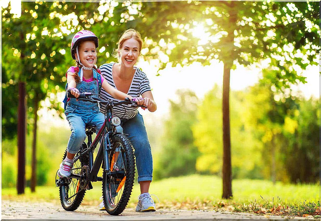 A mother teaching her daughter to ride a bike.