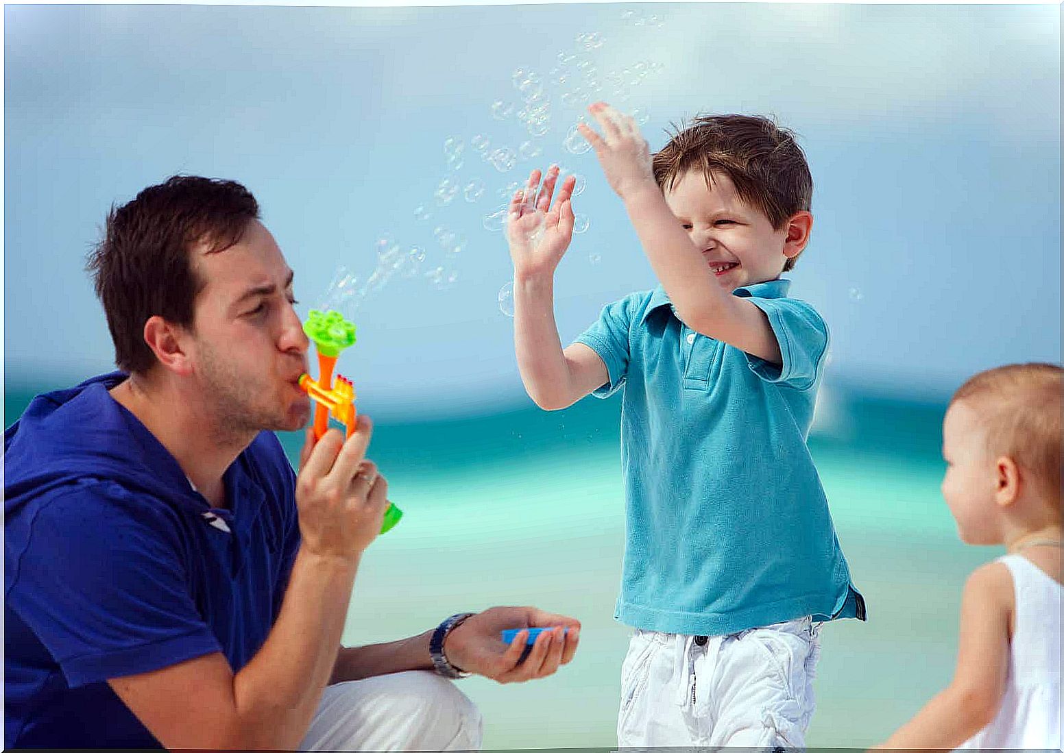 A father blowing bubbles with his children.