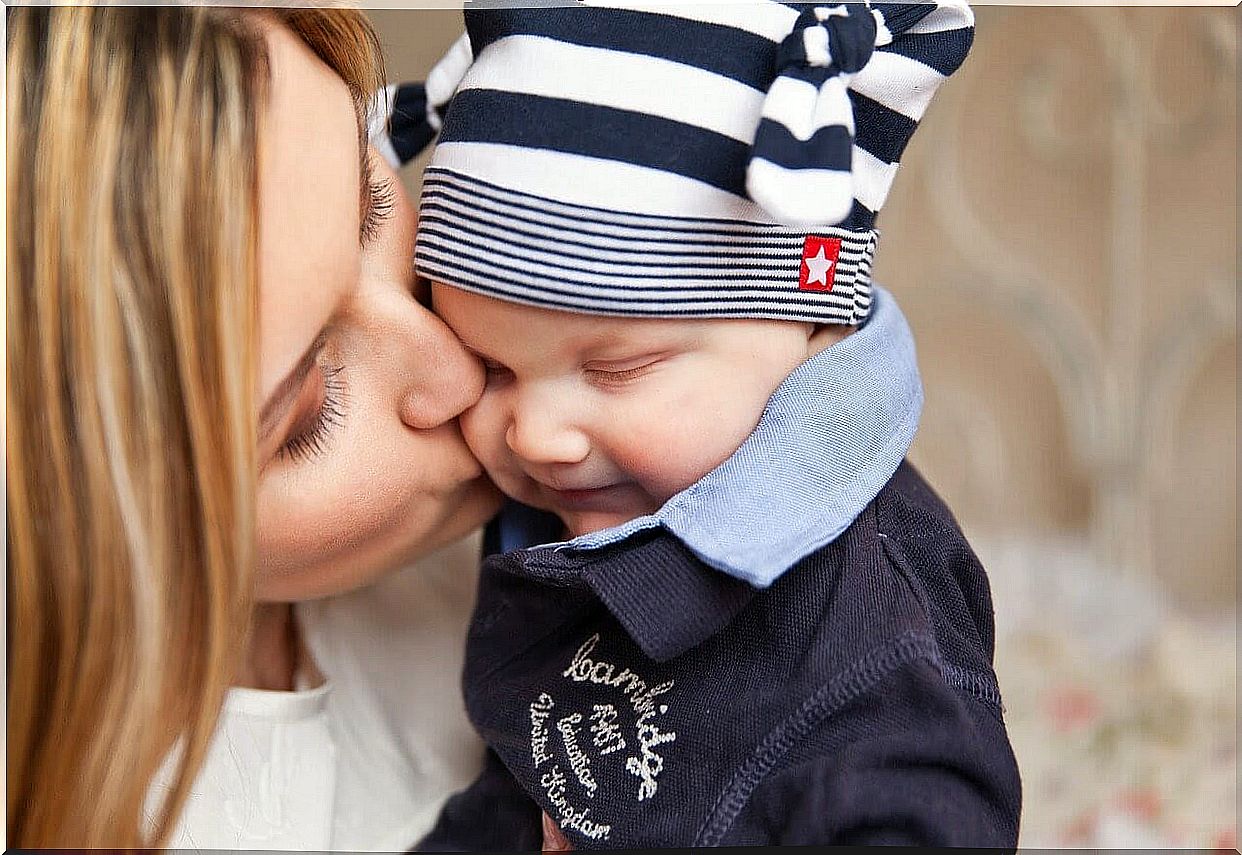 mom kisses baby with hat