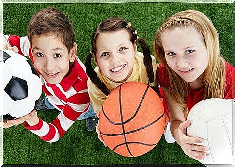 Three happy children look into the camera and hold balls